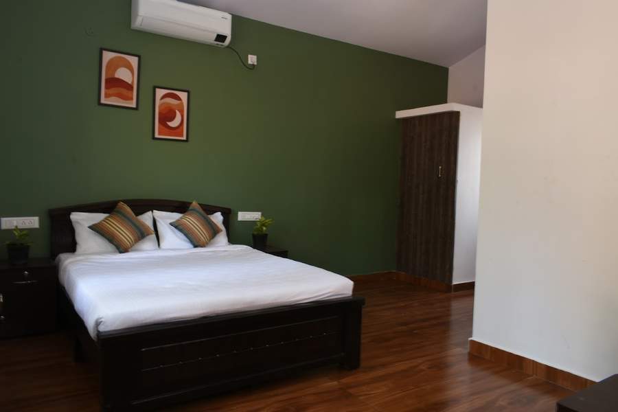 Deluxe AC room with green accent wall and double bed
